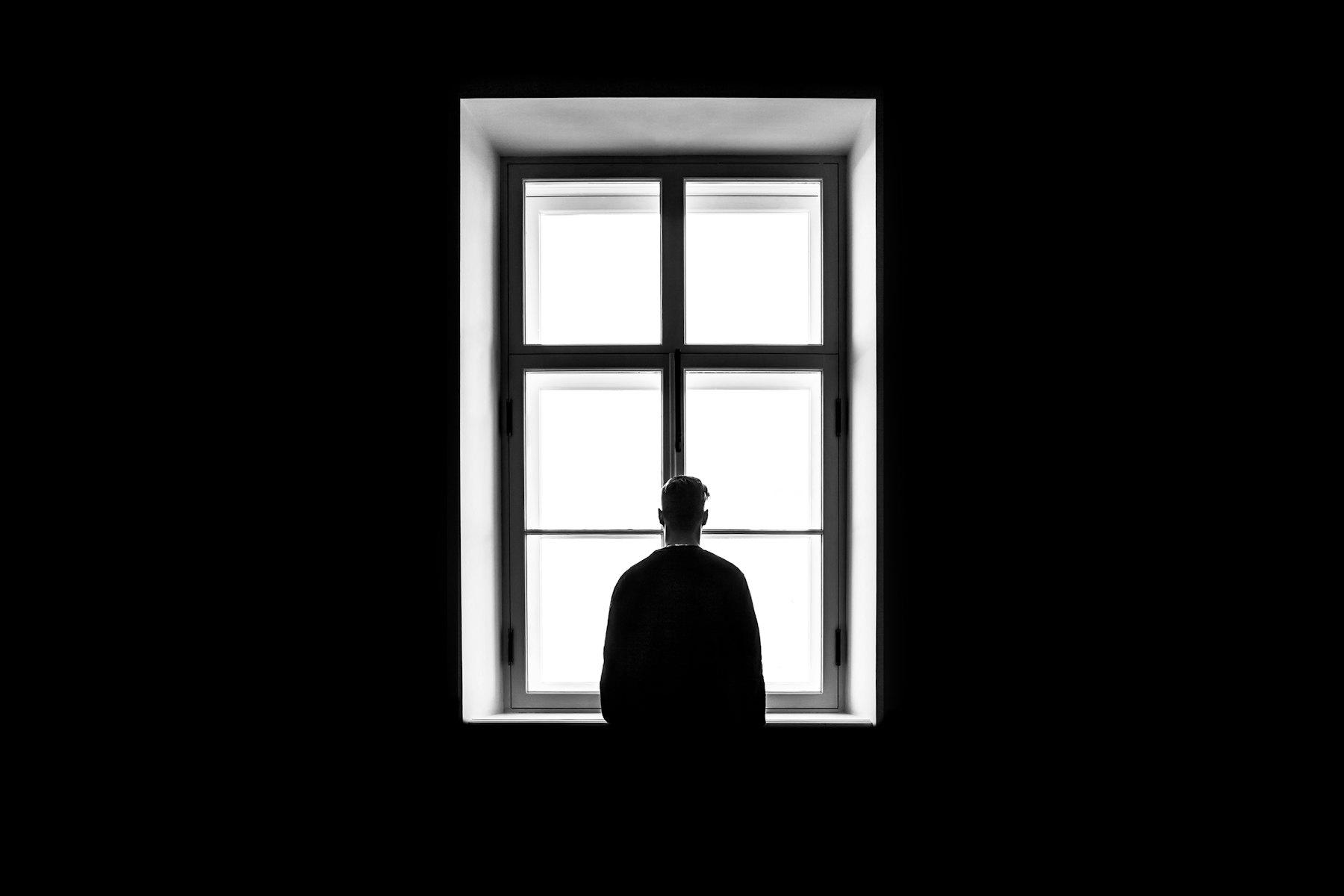 Une silhouette de dos devant une haute fenêtre